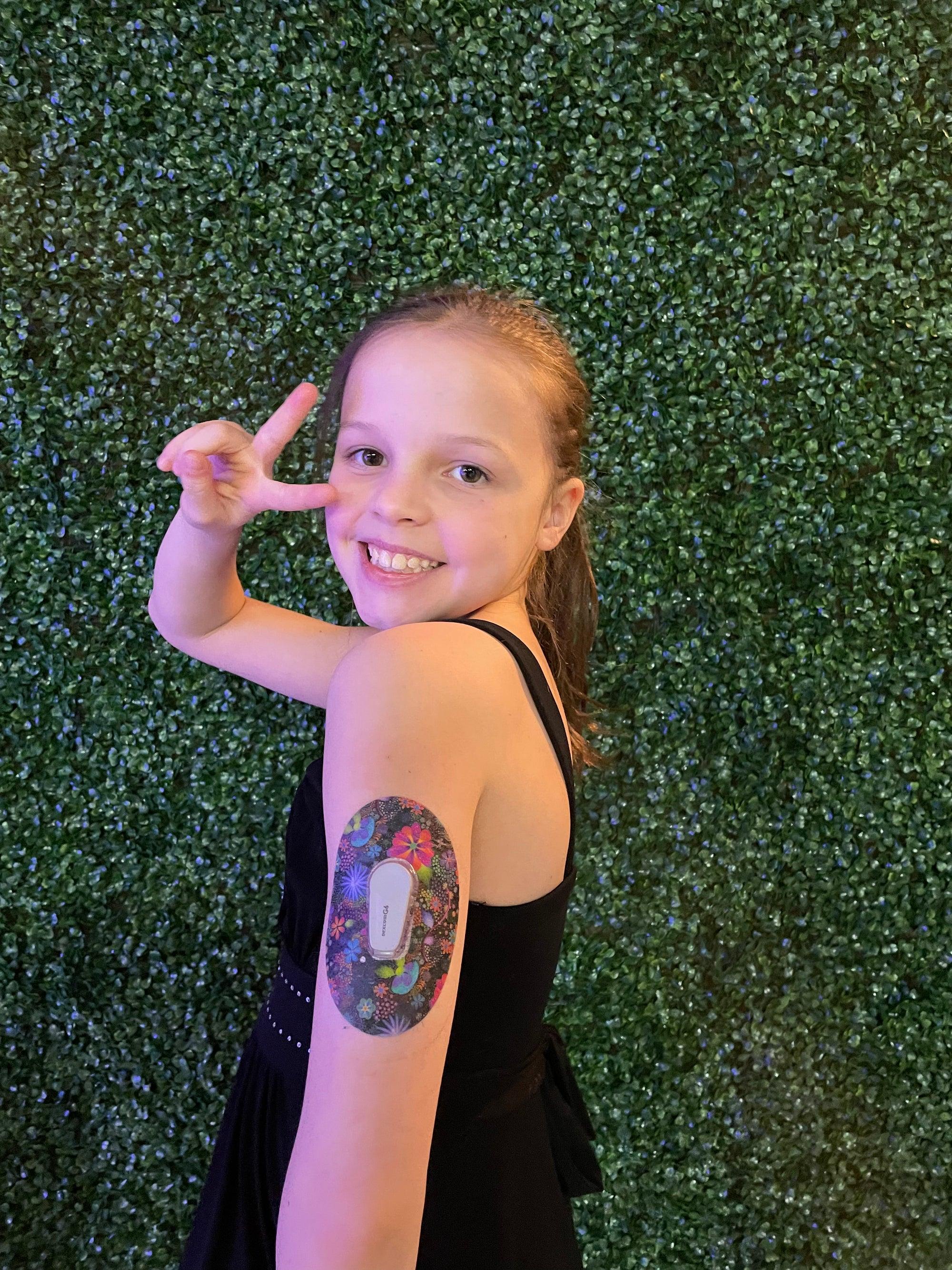 ExpressionMed Young girl holding up peace sign with Psychedelic Flowers Dexcom G6 Tape on arm