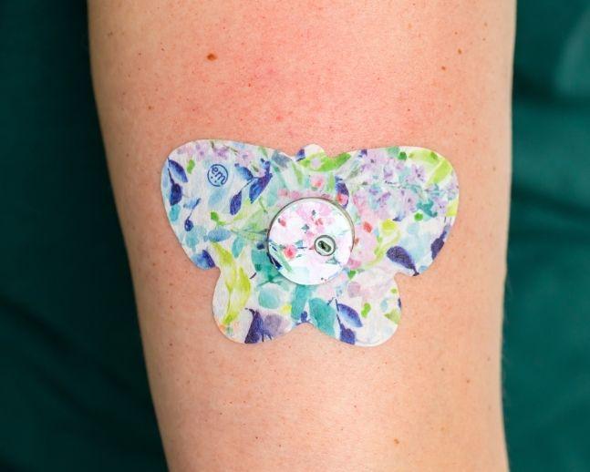 ExpressionMed, Subdued Tropics Libre 3 Transmitter Sticker, Tape & Sticker, Human Wearing Subdued Tropics Themed CGM Adhesive Patch Design
