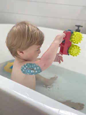 ExpressionMed Little boy playing in the tub with Pawprint Dexcom G6 Tape and Transmitter Sticker on his arm