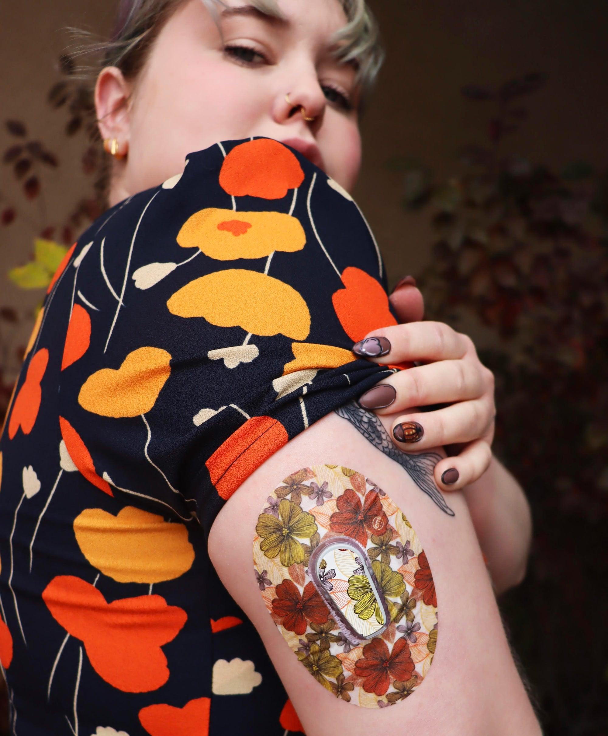 Woman with Burnt Orange Floral Dexcom G6 Tape and Transmitter Sticker on arm