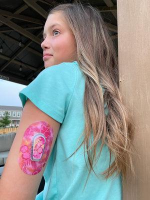 ExpressionMed Girl with pink hibiscus dexcom G6 mini tape and transmitter sticker on arm